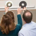 Two people hold up tape reels to the light