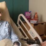 A man in a hospital bed talks to a woman