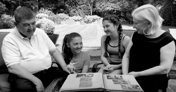 Argun, showing the photograph album he rescued from his grandfather's bombed out house in Cyprus, to his wife, Hurmus and grandchildren, Aleyna and Alara. From the film Life is a Destiny, courtesy of Child Migrant Stories.