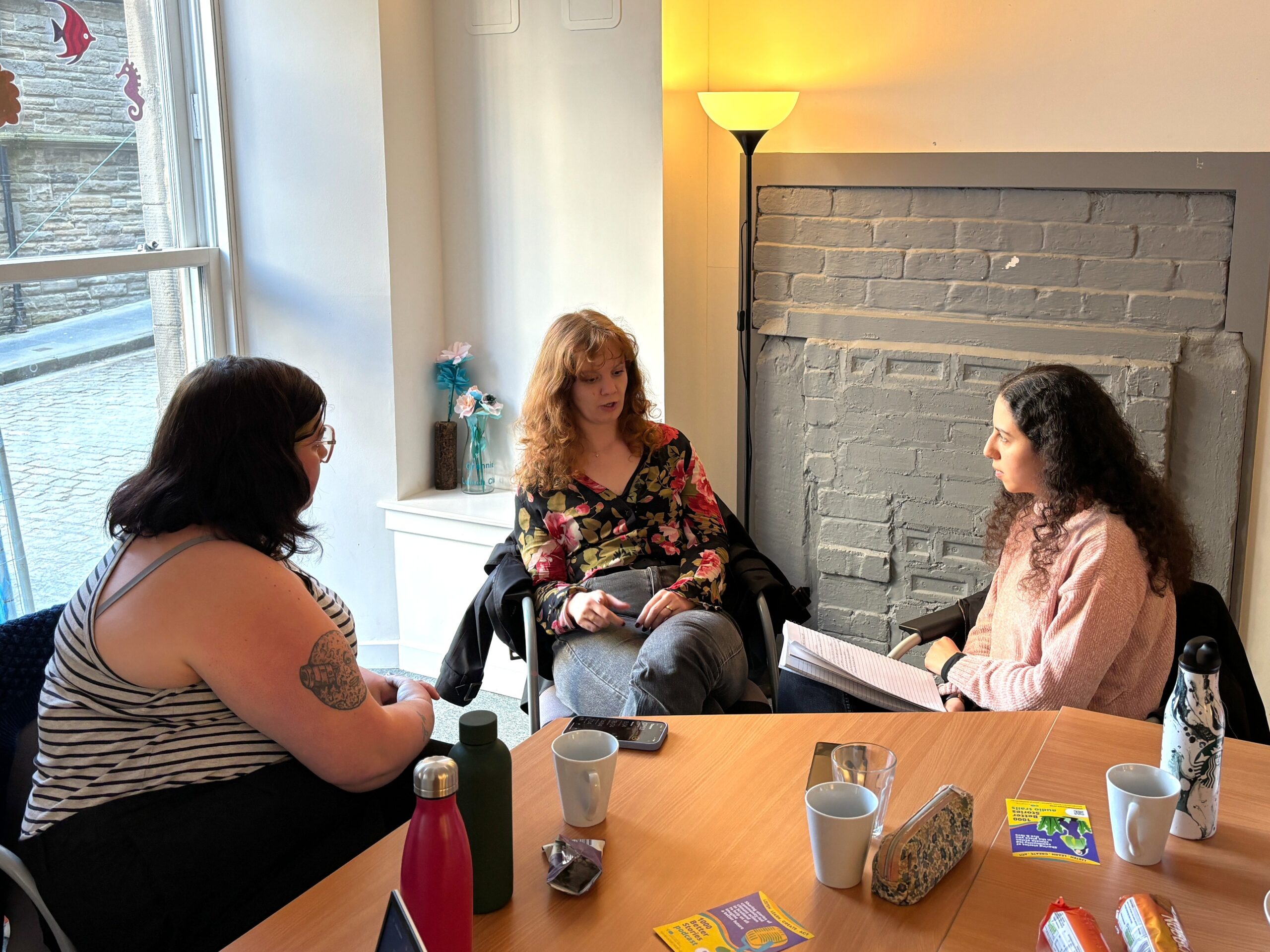 Three people sit talking around a table
