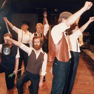 Actors on stage with their arms raised